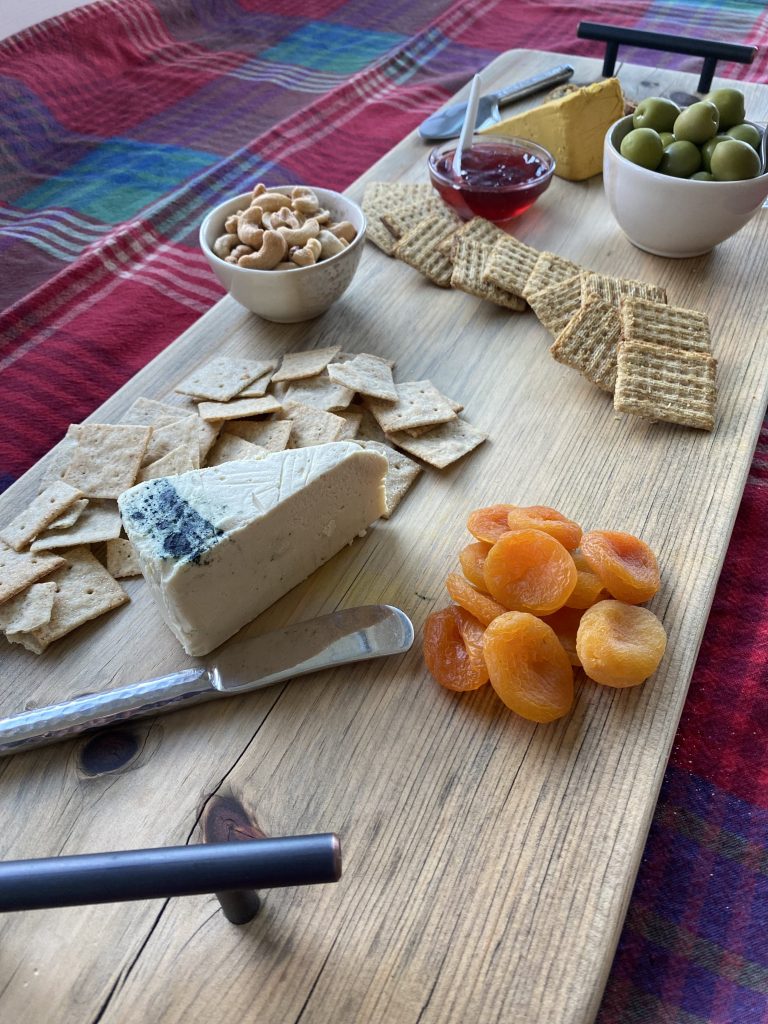 healthy vegetarian charcuterie board with crackers, fruit, olives and vegan cheese
