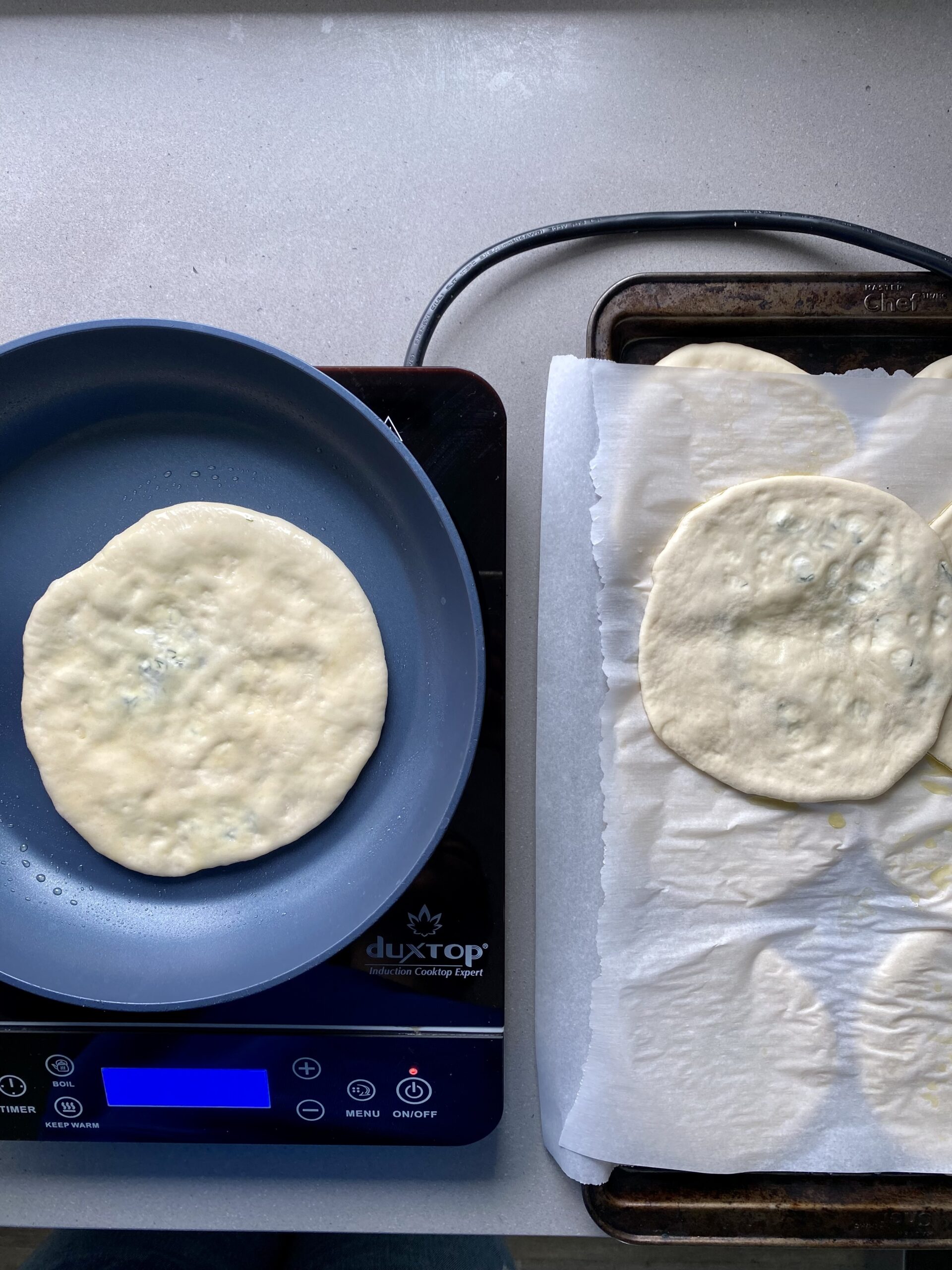 rolled out pita on a pan cooking.