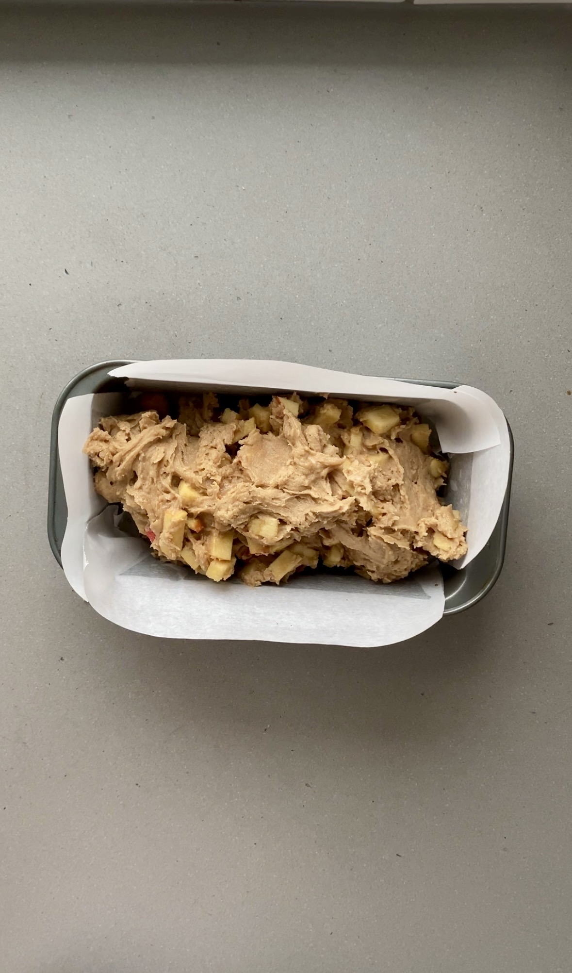 batter added to the parchment paper lined loaf pan, ready for baking.