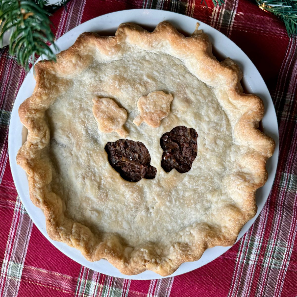 vegan meat pie in a white pie plate on a holiday placemat.