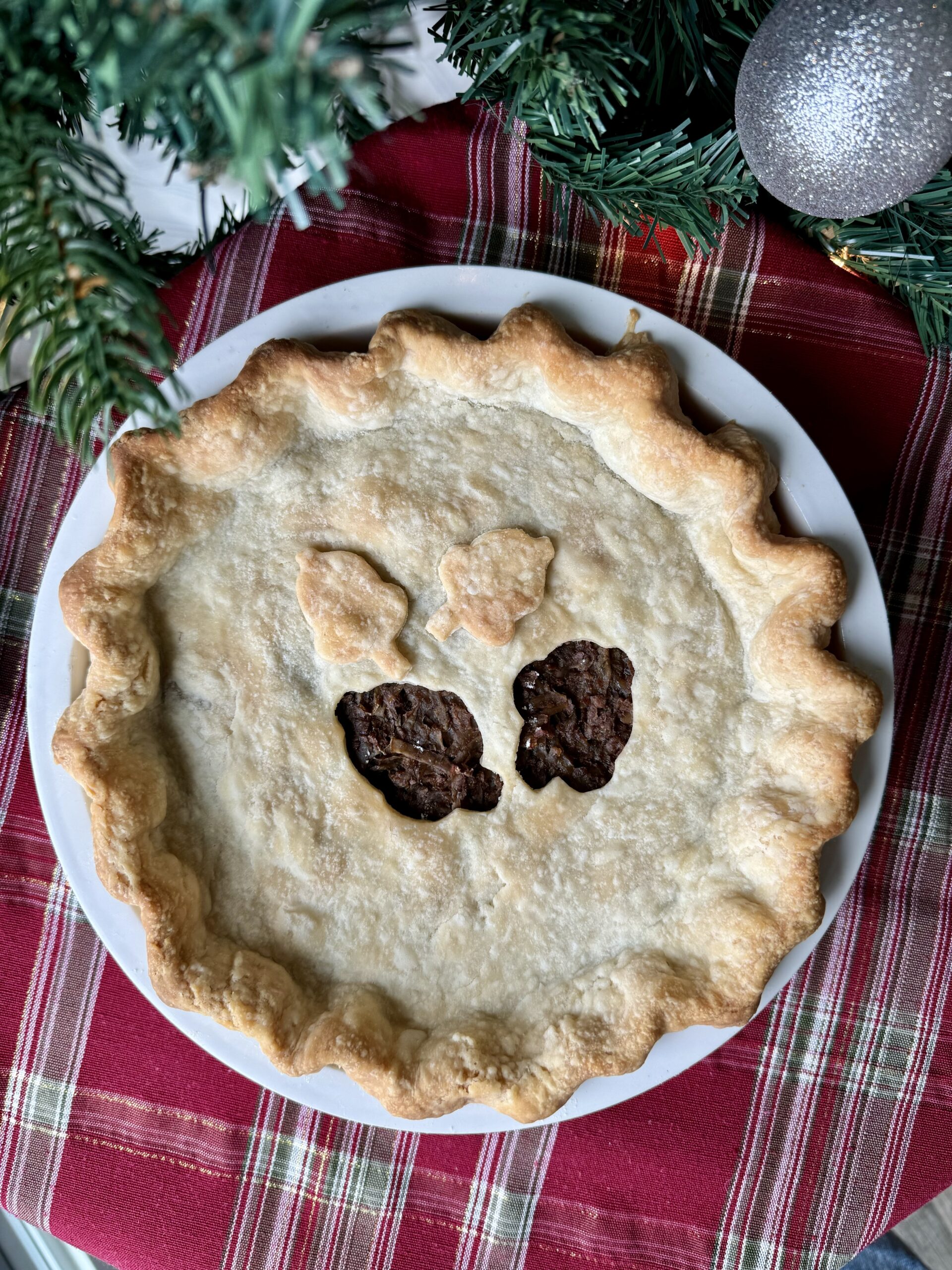 vegan meat pie in a white pie plate on a holiday placemat.