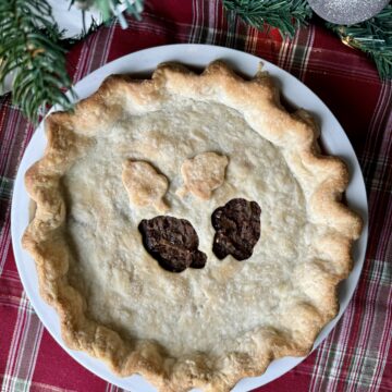 vegan meat pie in a white pie plate on holiday placemat