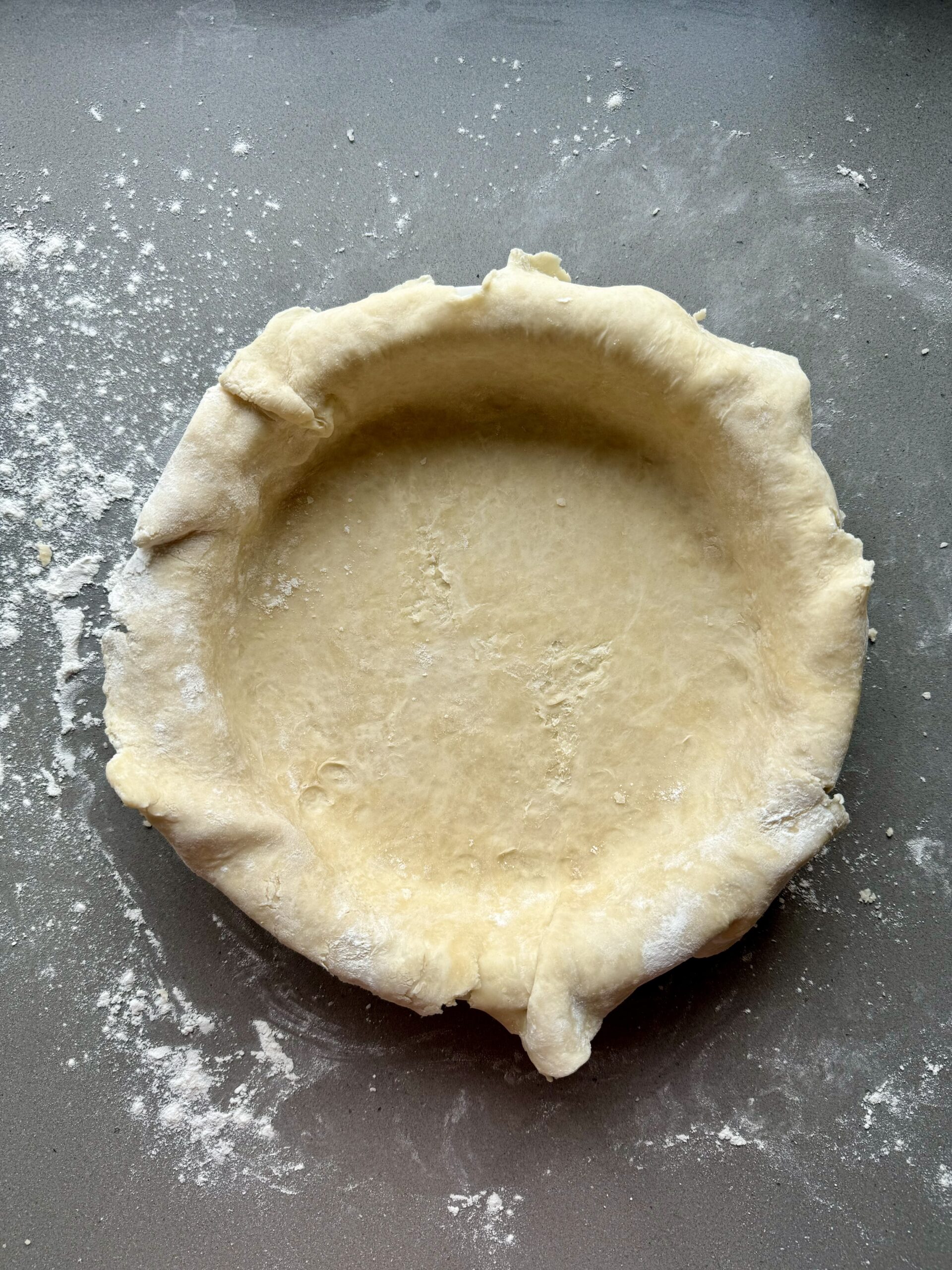 pie dough trimmed in a pie plate.