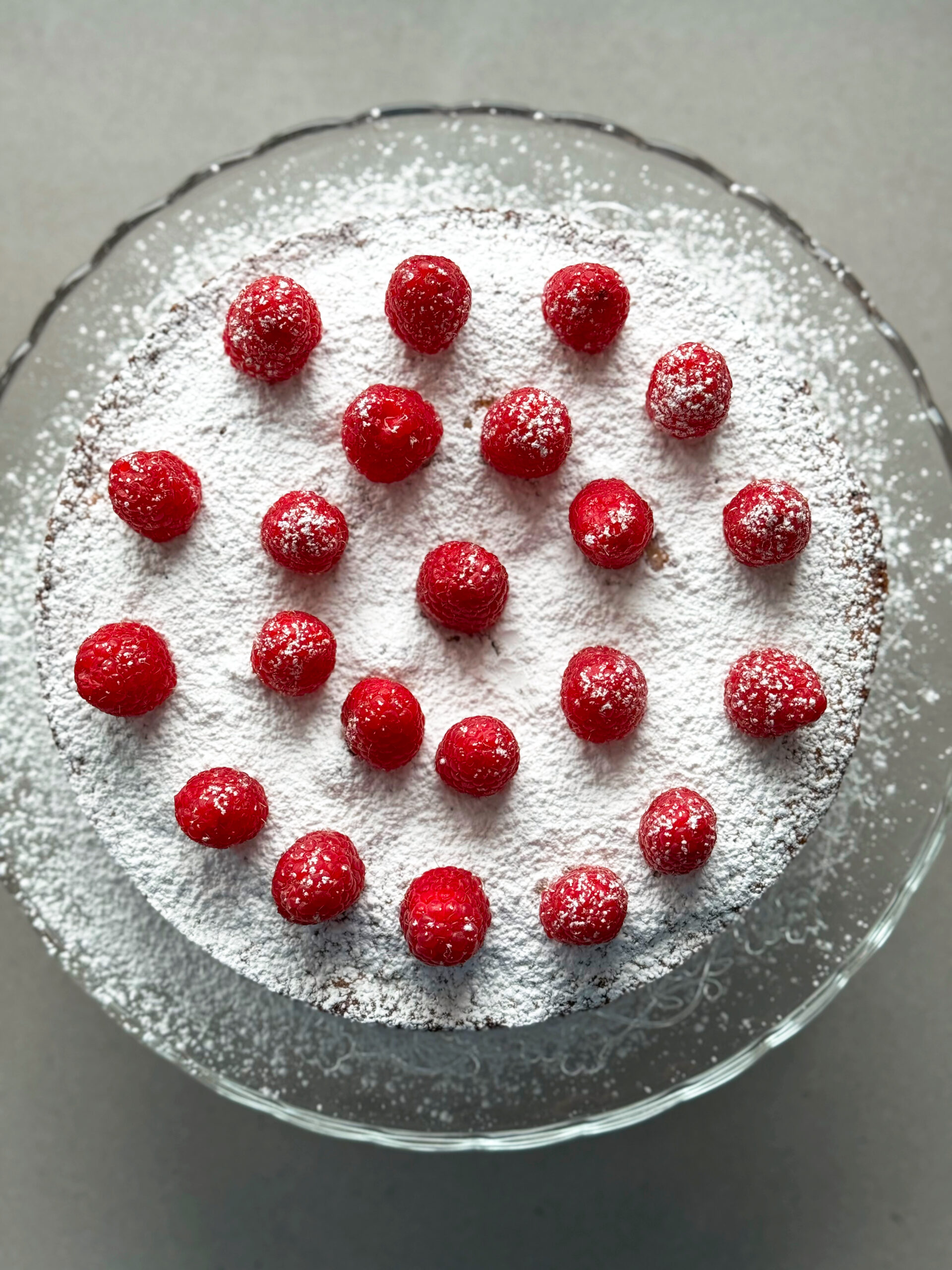 almond raspberry cake with fresh raspberries on top.