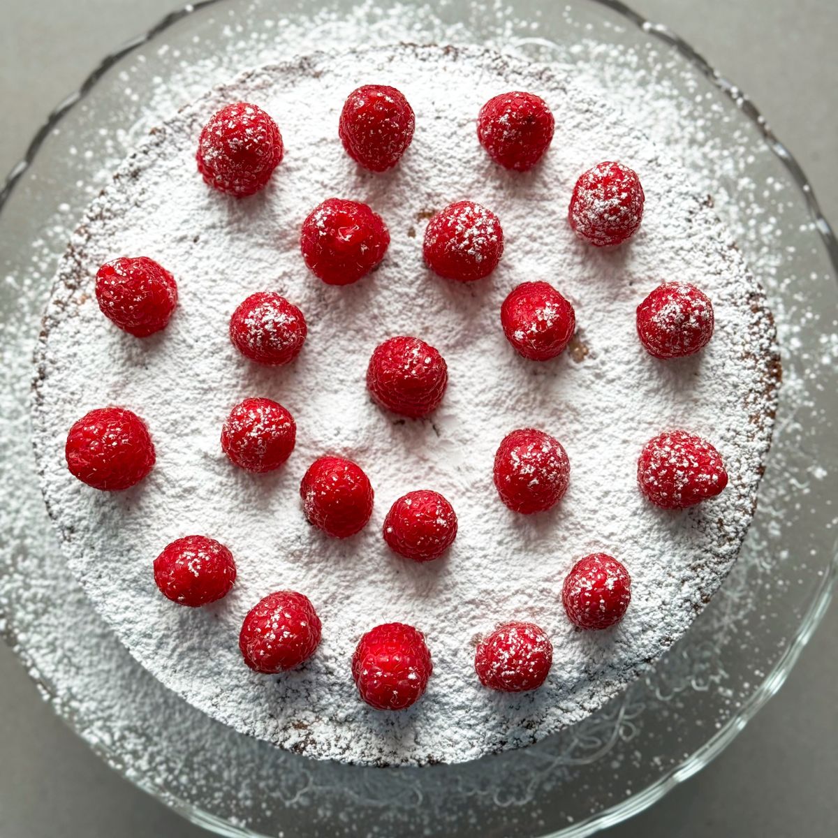 almond raspberry cake with fresh raspberries on top.