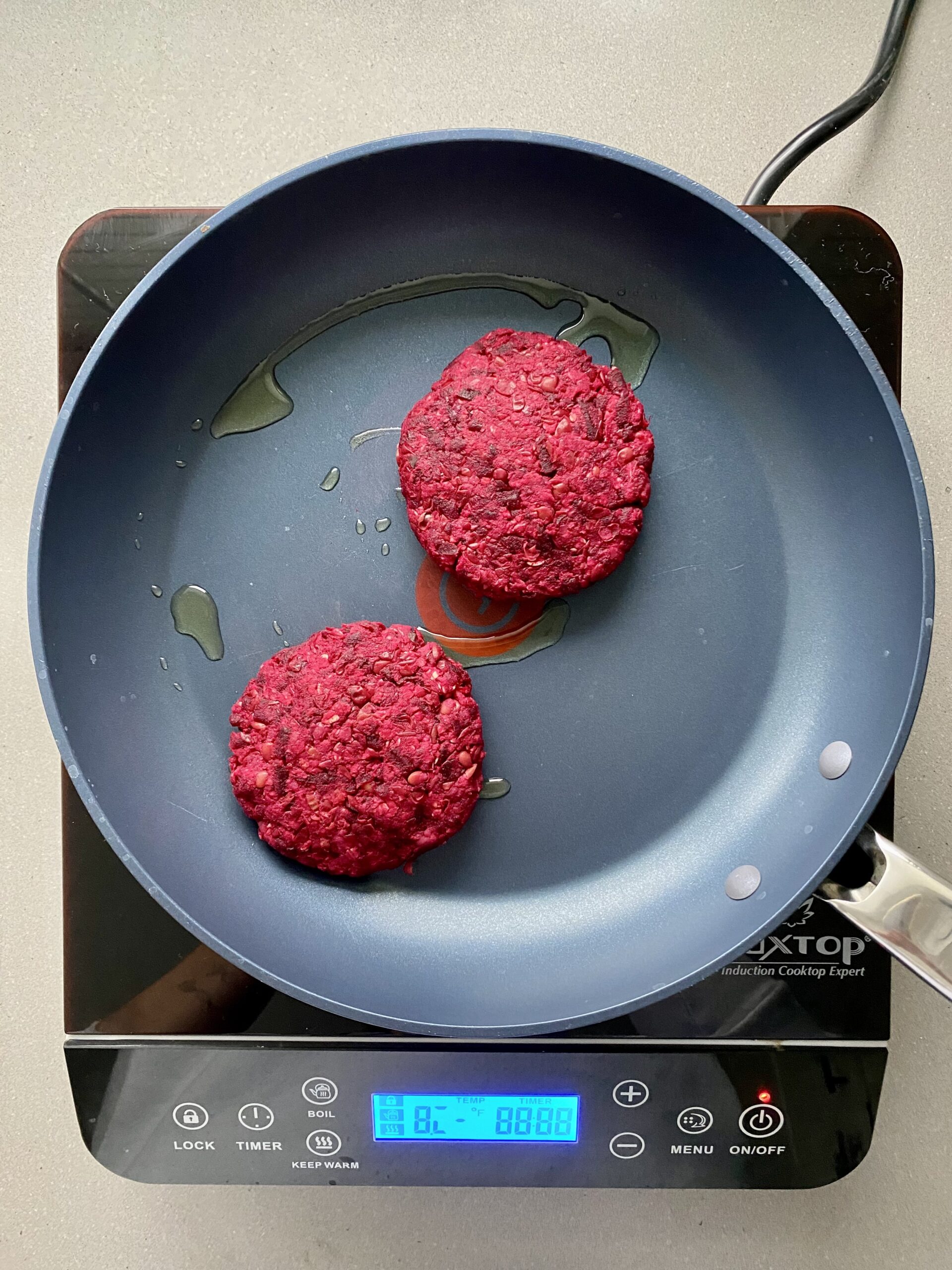 beet burger patties on a pan cooking.