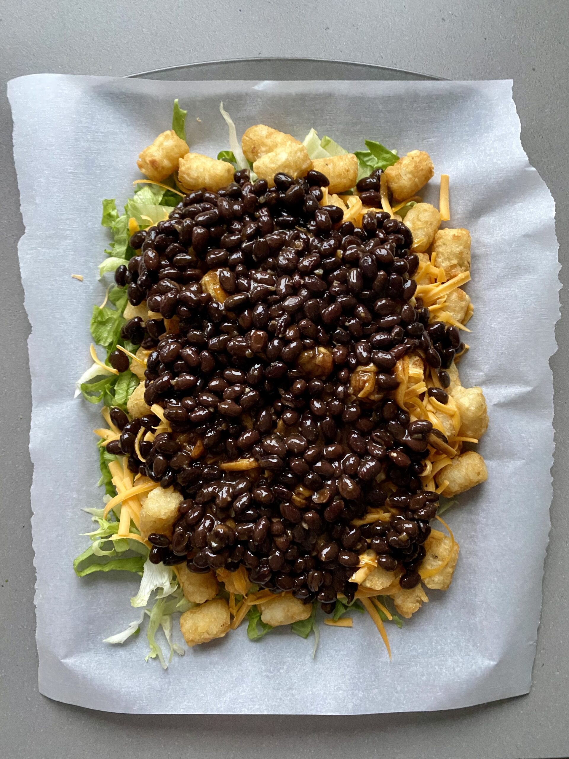 cheese and black beans layered on the lettuce and tater tots.