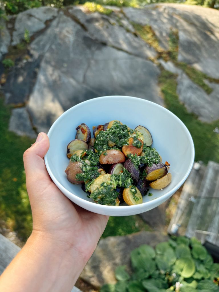 herby dressing on roasted potatoes in a bowl