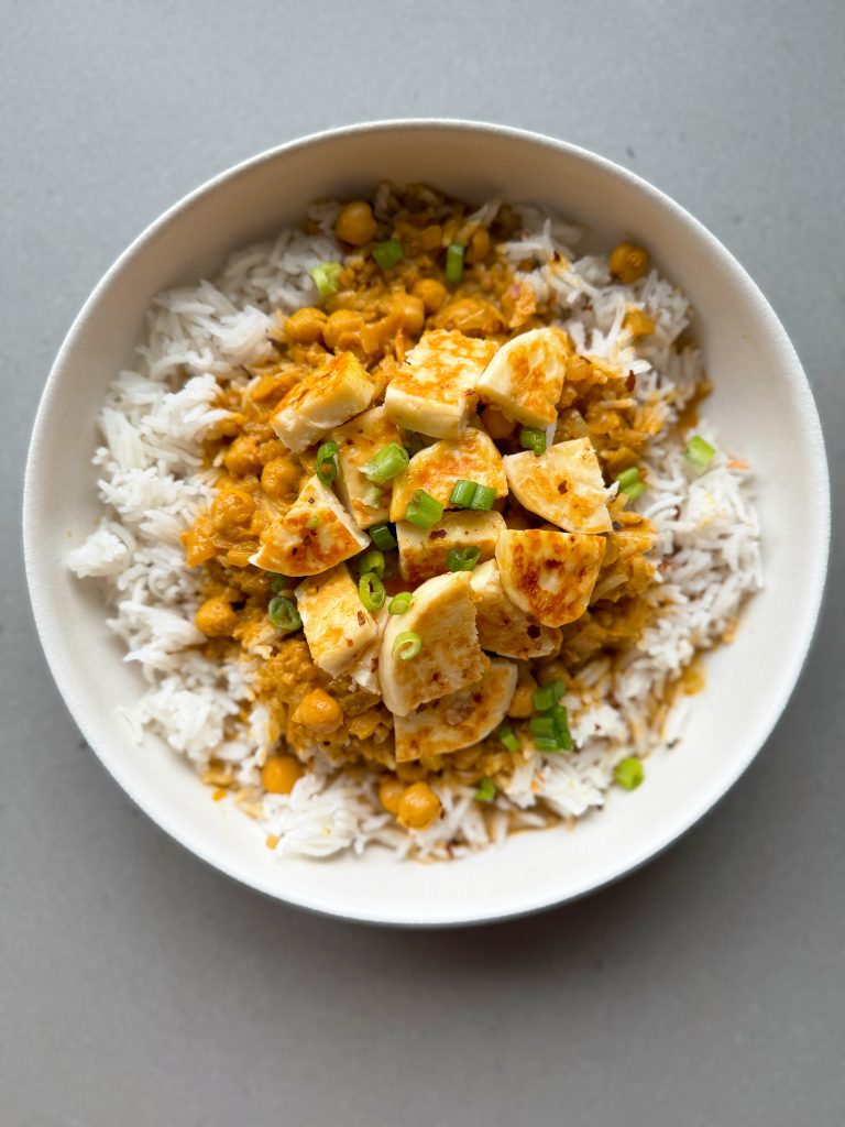 butter halloumi curry on rice in a bowl