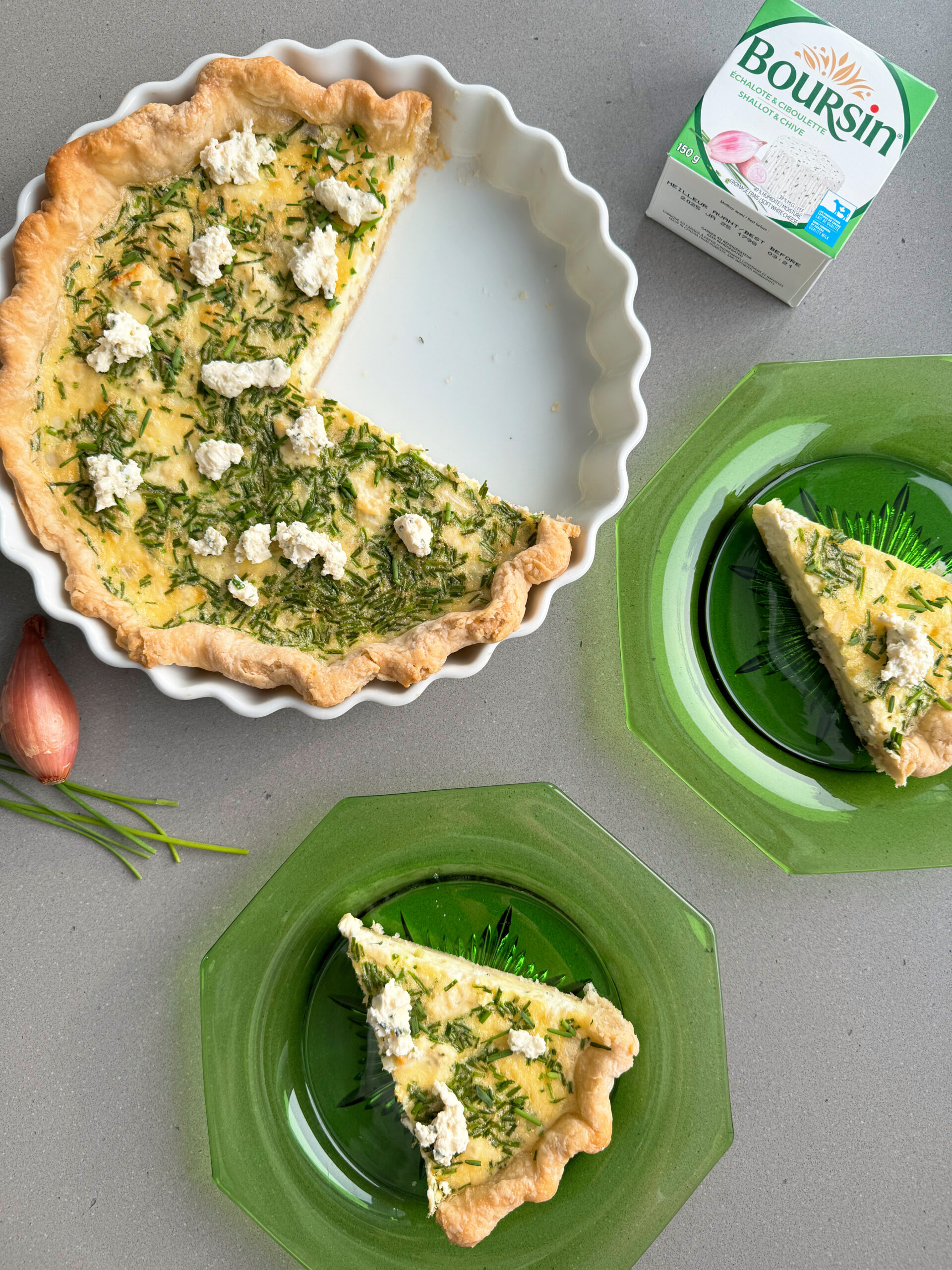 boursin quiche with 2 slices cut and served on green plates.
