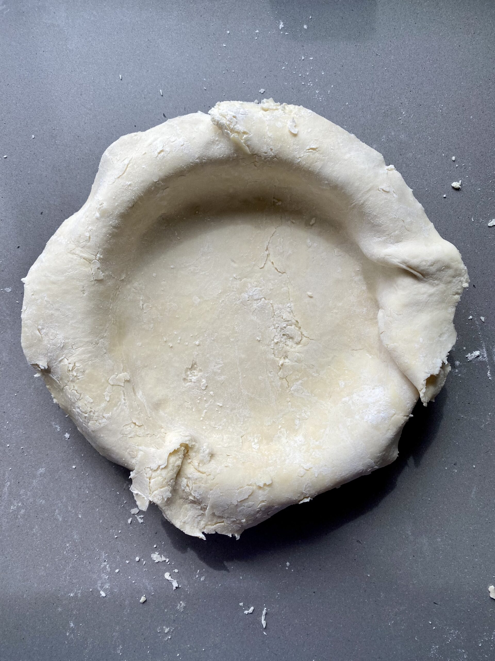 pie dough in a pie plate, edges trimmed.