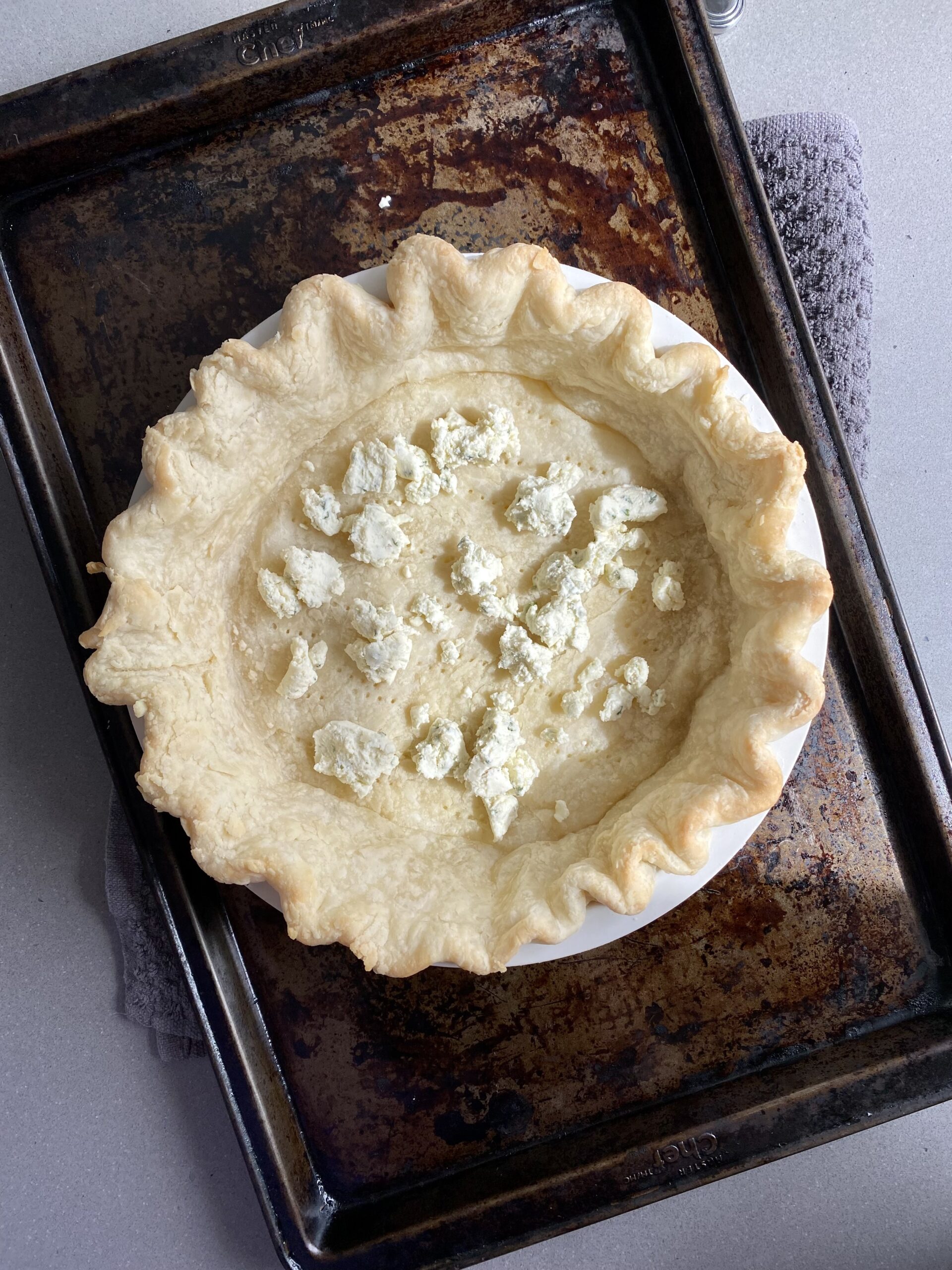 blind baked pie crust with pieces of boursin cheese on the bottom.