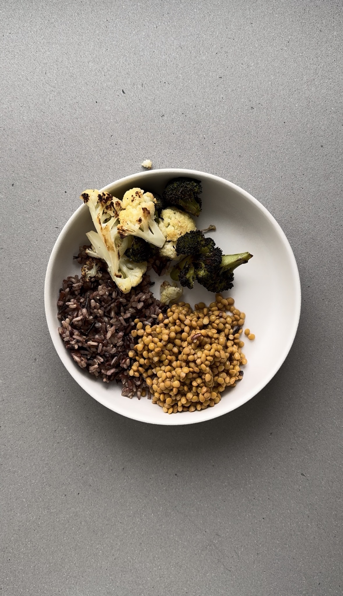 roasted broccoli and cauliflower added to a white bowl.