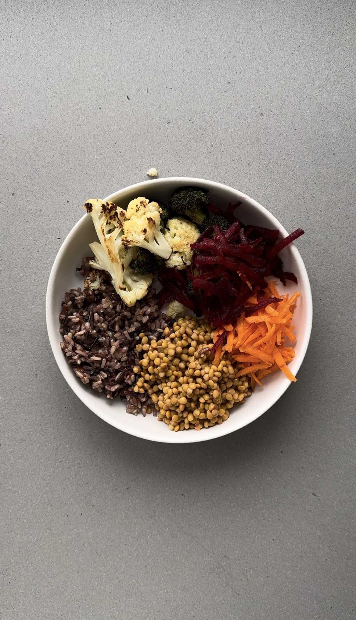 shredded carrot and beet added to a white bowl.