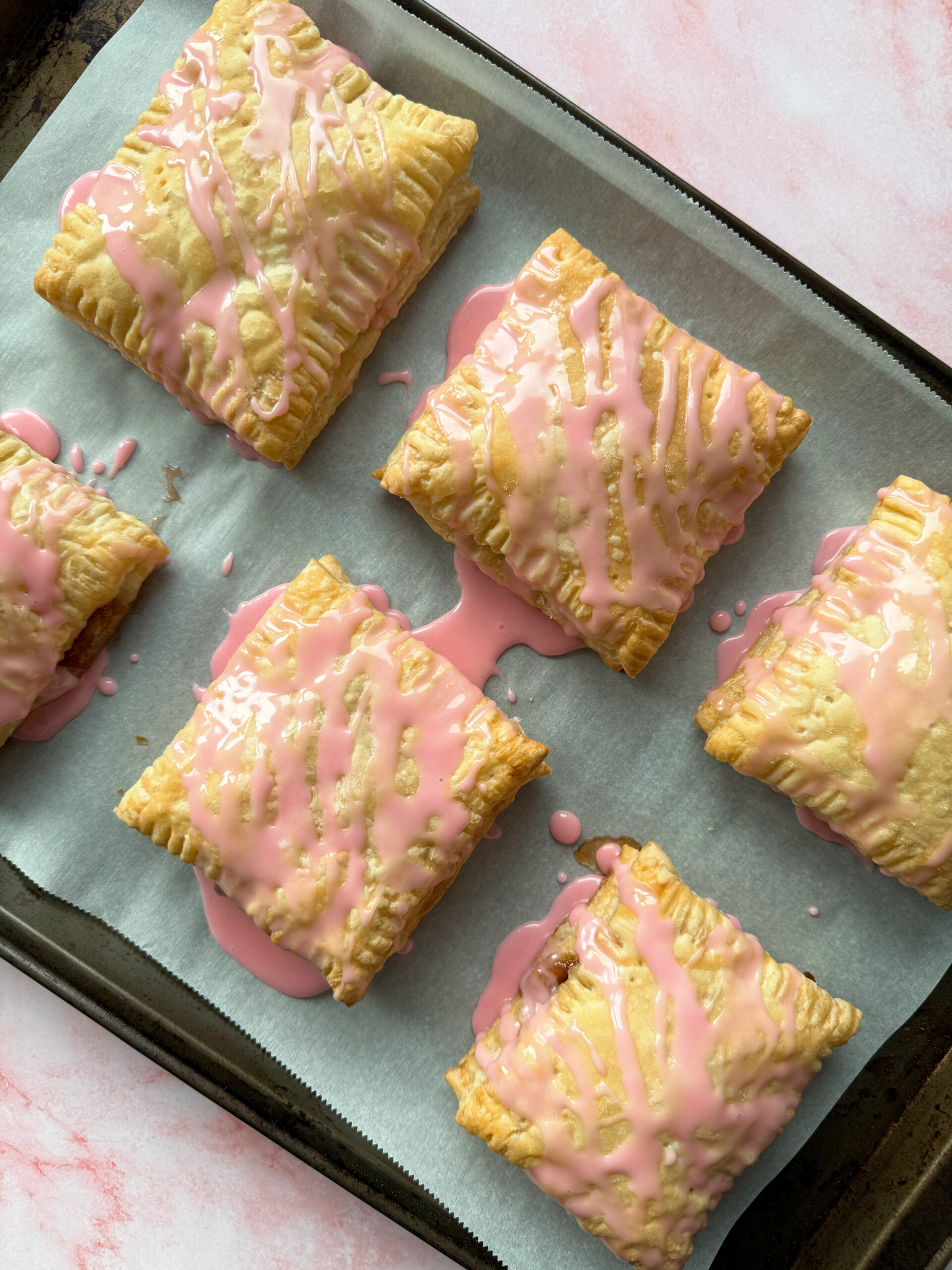 baked puff pastry strawberry pop tarts with icing on top.