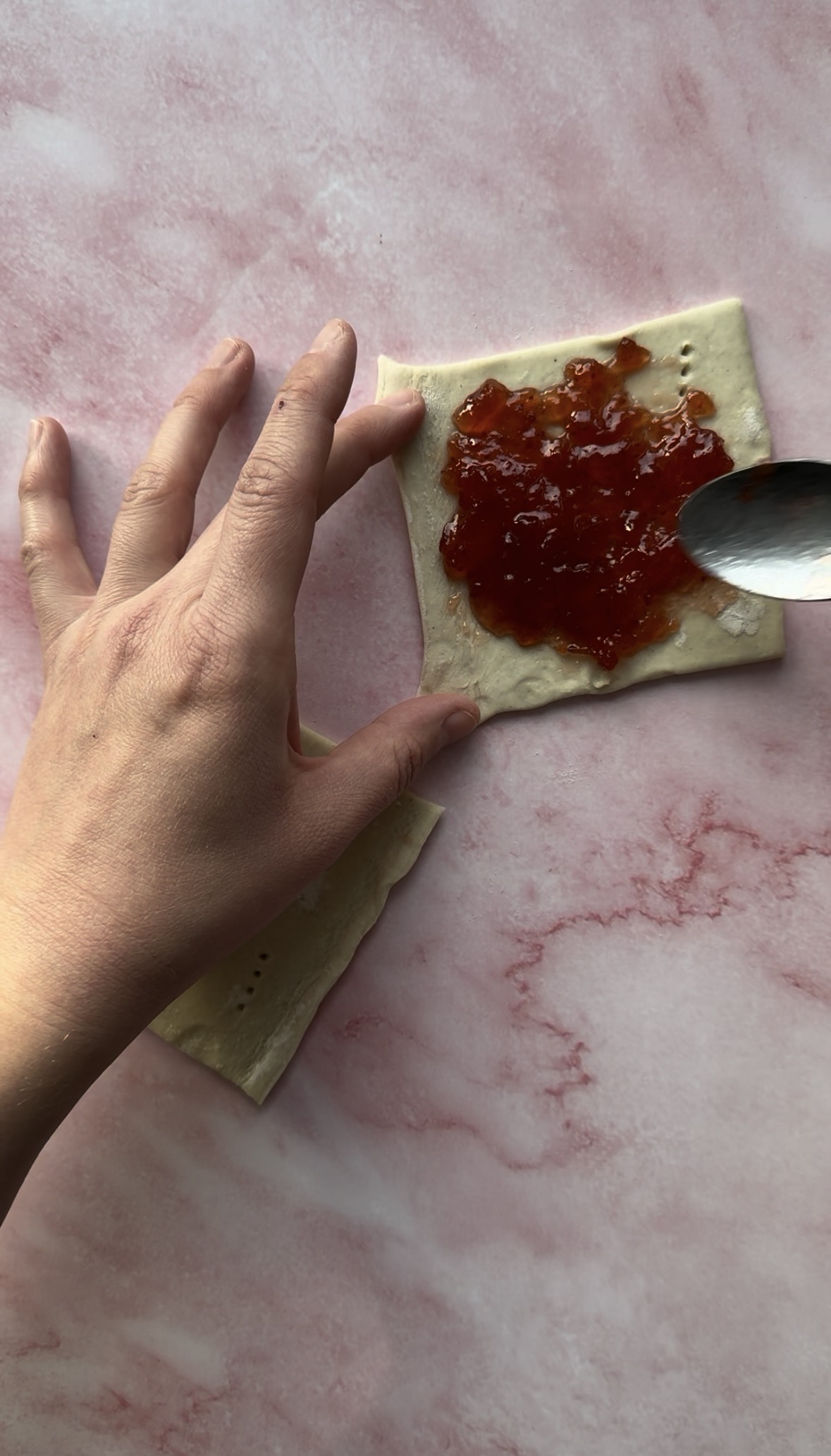 puff pastry with jam being added to one of them.