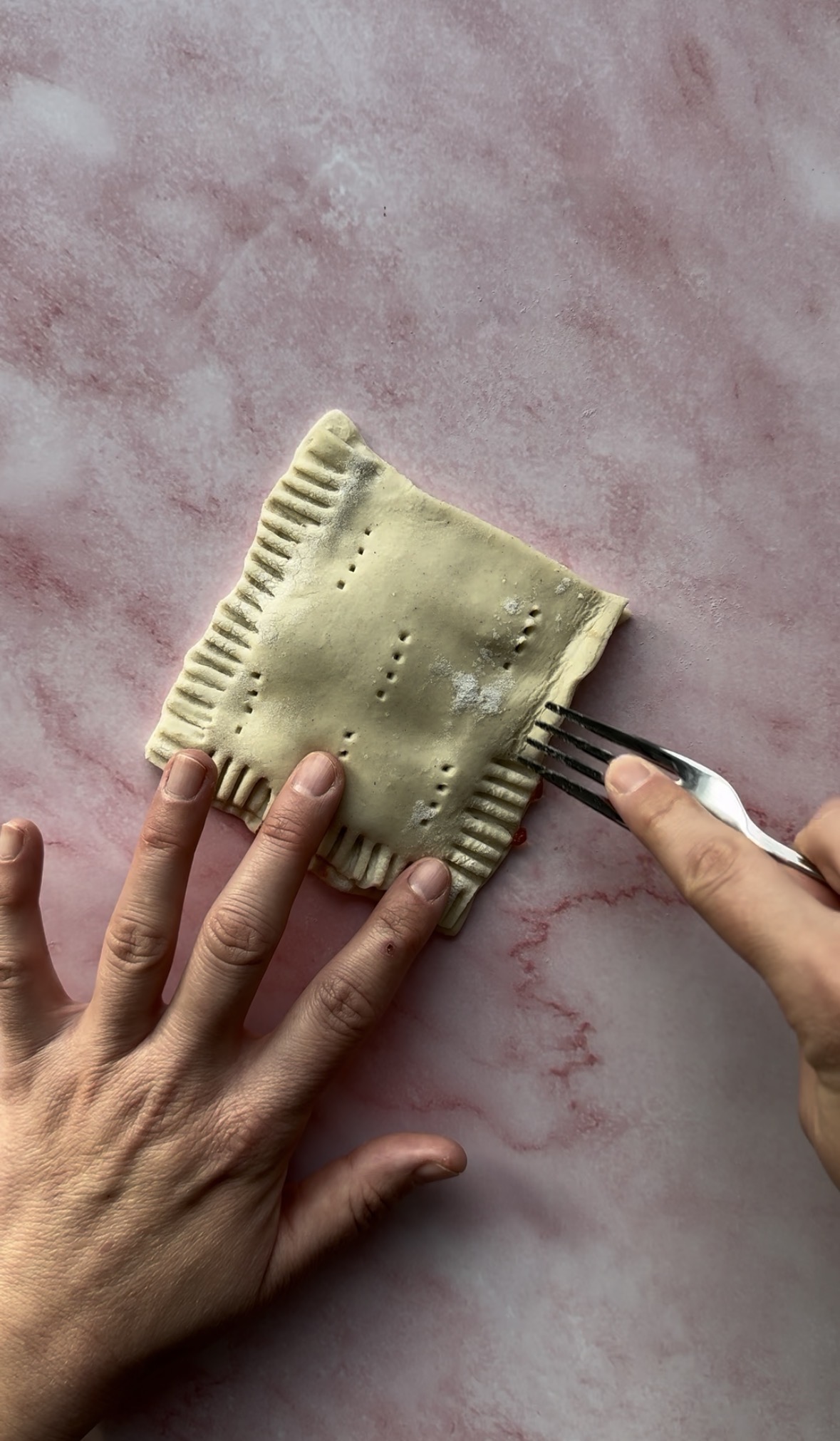 top puff pastry layer added on top and seams being sealed with a fork.