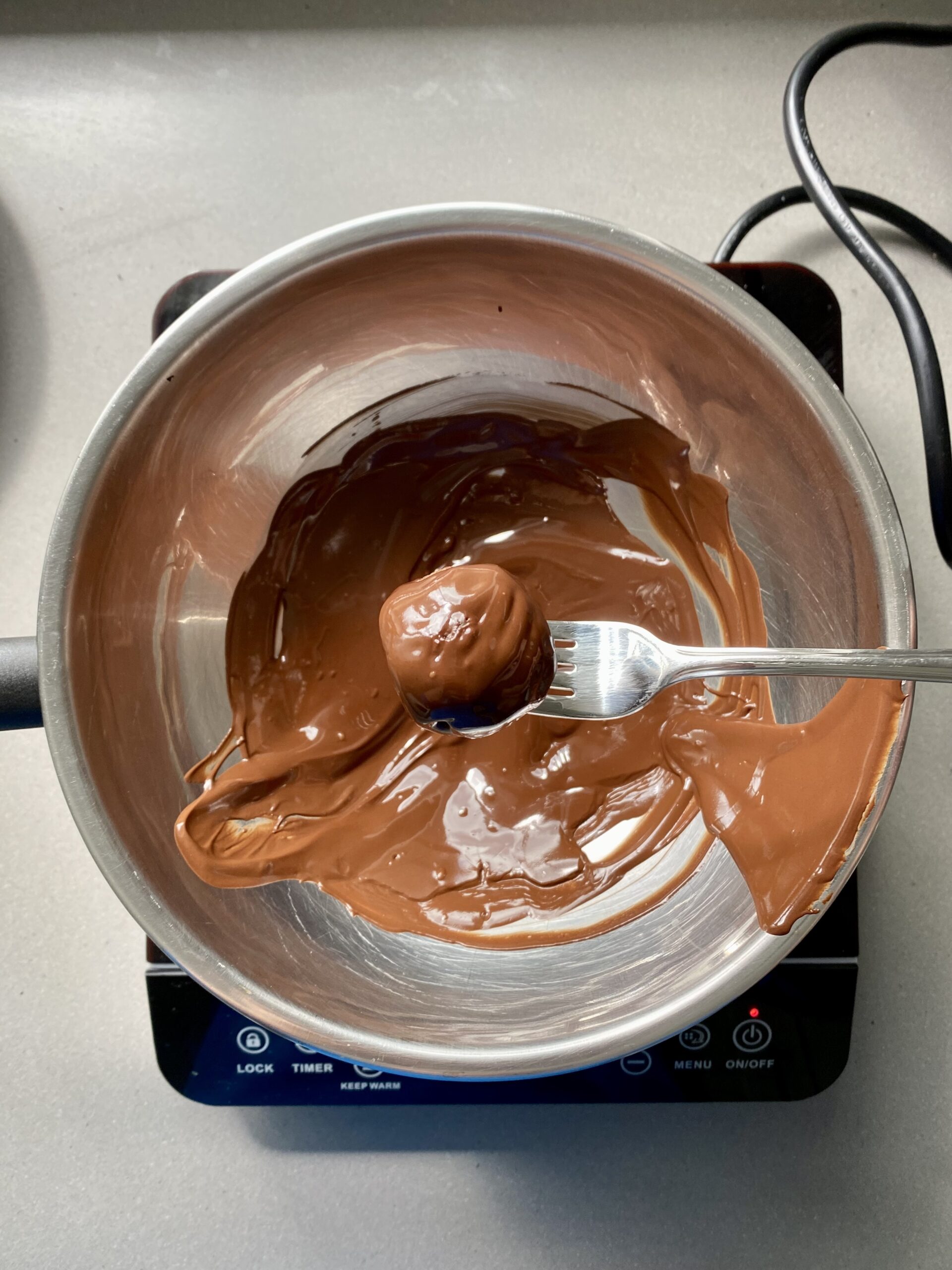 date ball being dipped in melted chocolate.
