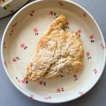 white chocolate pistachio scone on a pink flower plate