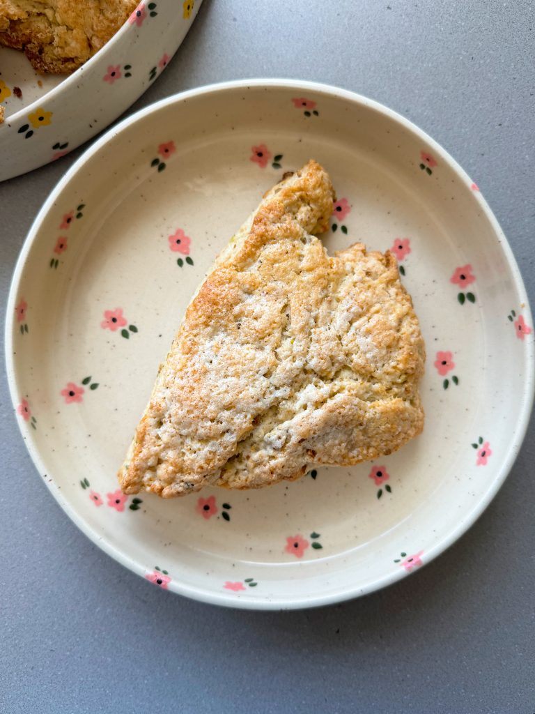 white chocolate pistachio scone on a pink flower plate