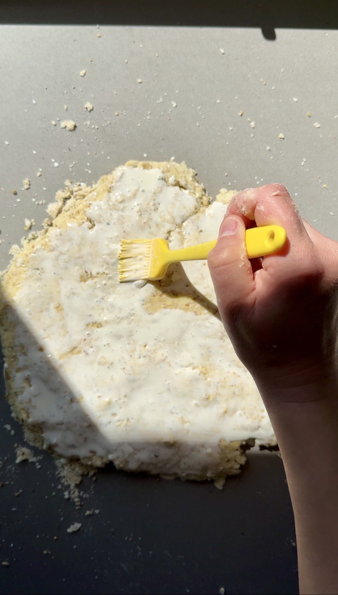 whipping cream being brushed on top of scones.