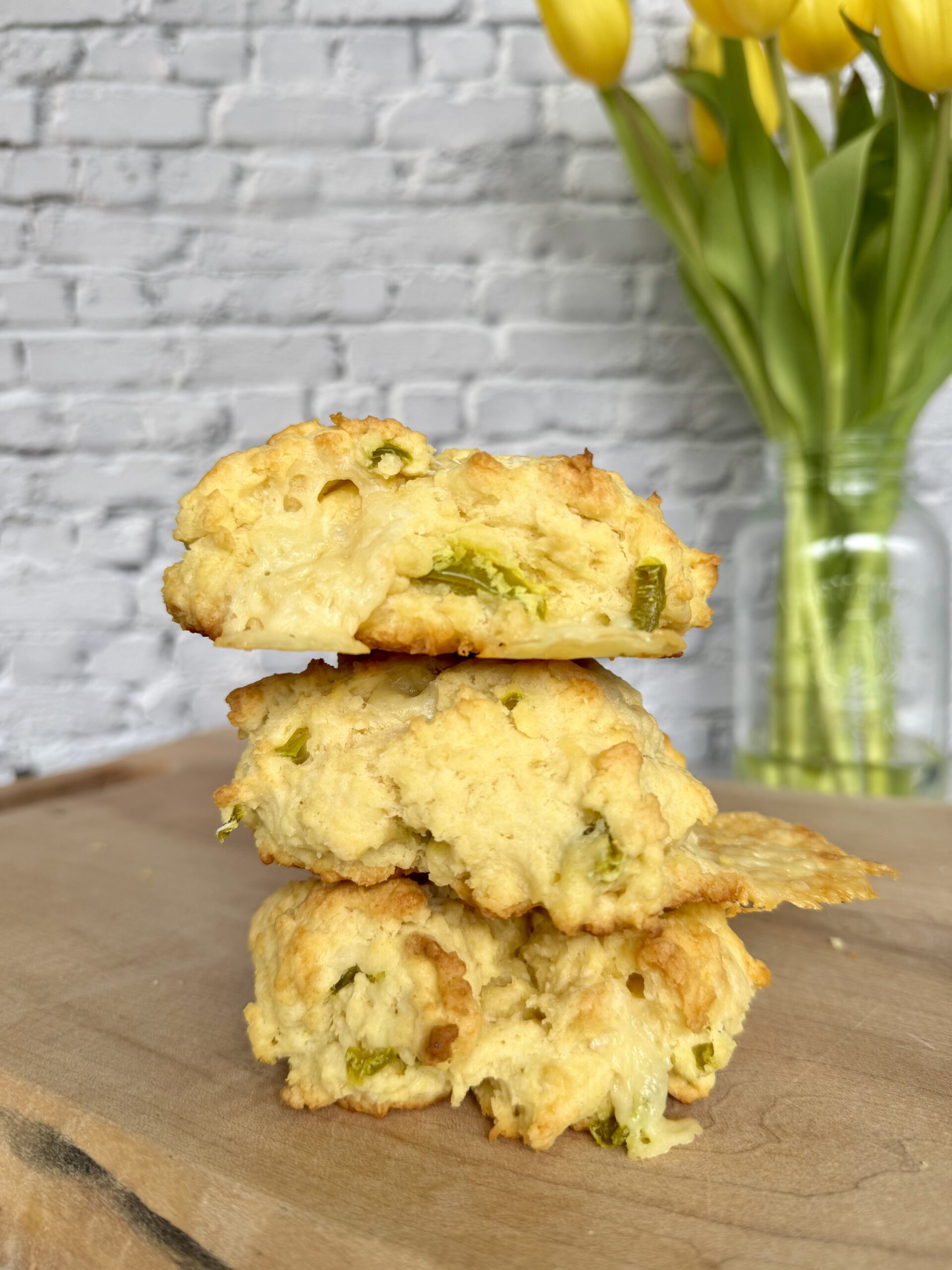 cheese drop biscuits stacked on a cutting board.