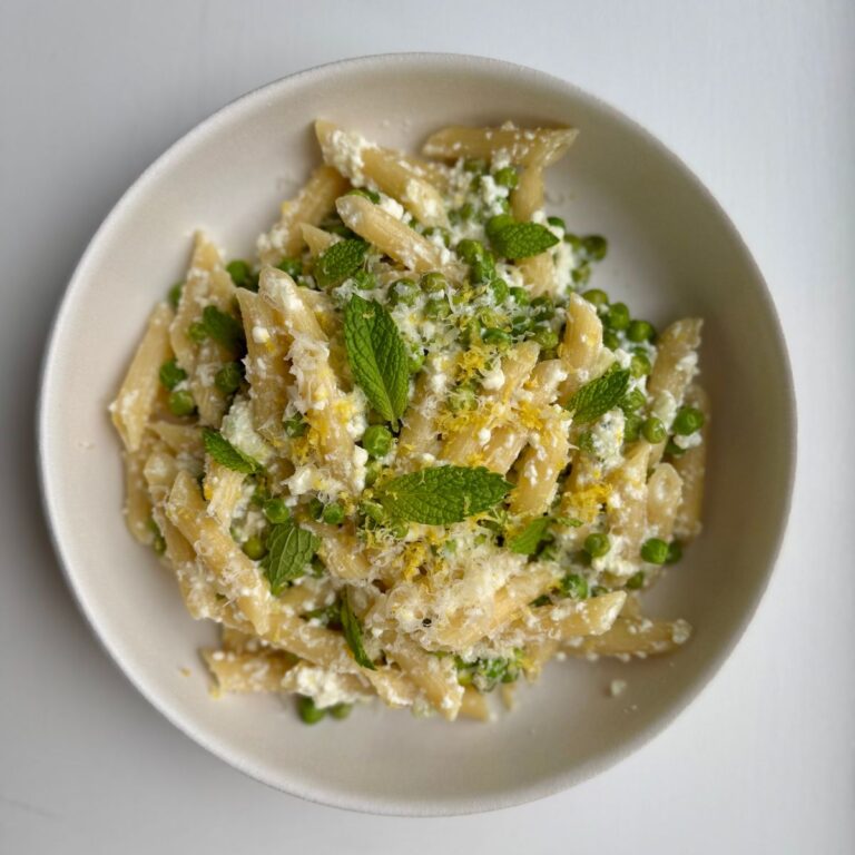 pea and ricotta pasta with garnishes in a white bowl.