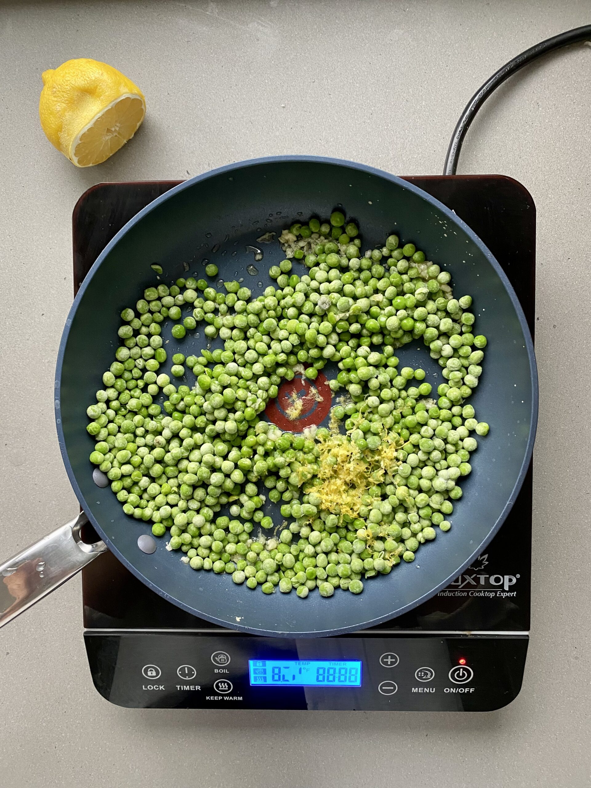 frozen pea and lemon zest in a frying pan.