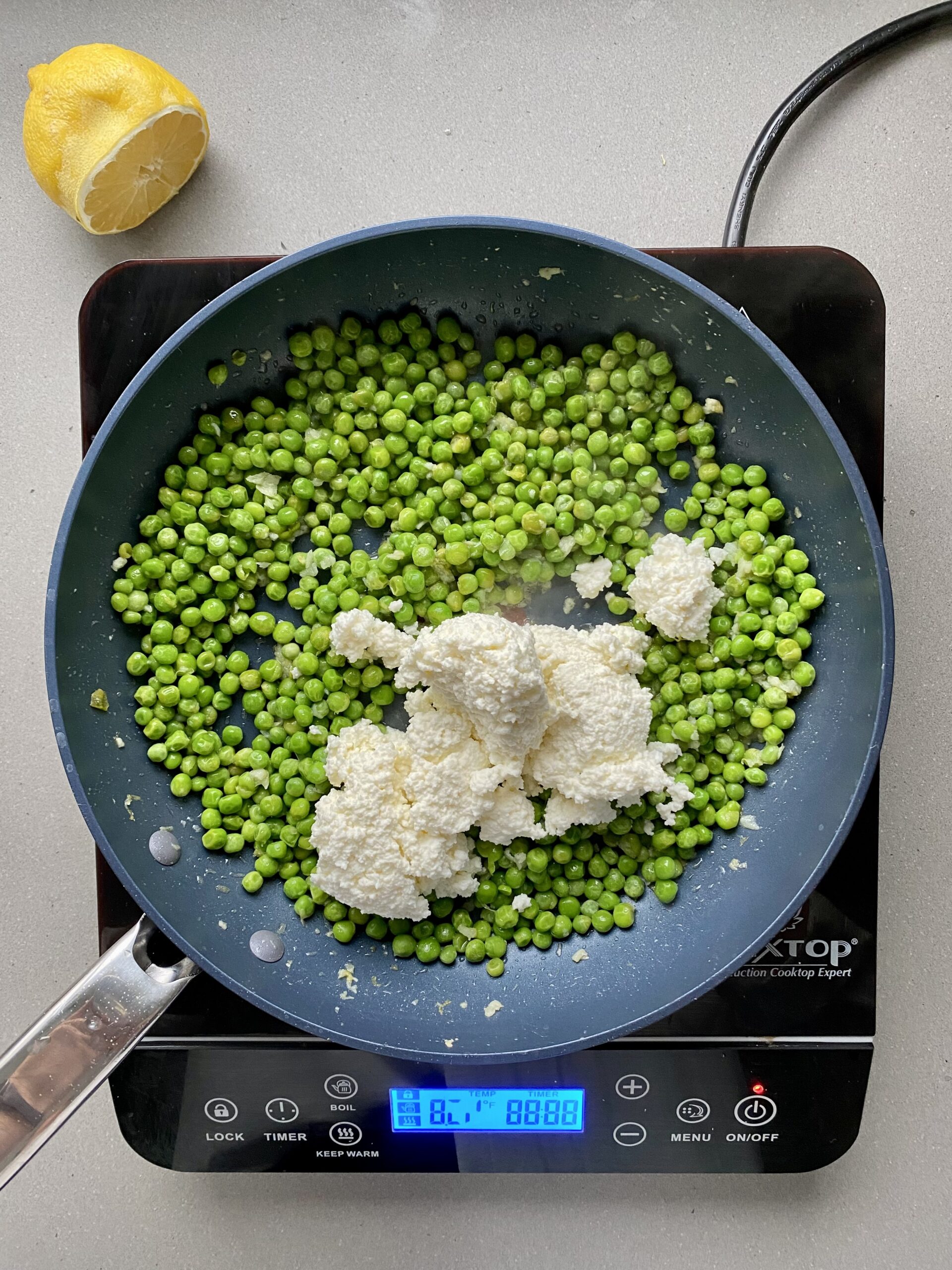 ricotta added to frozen peas in a frying pan.