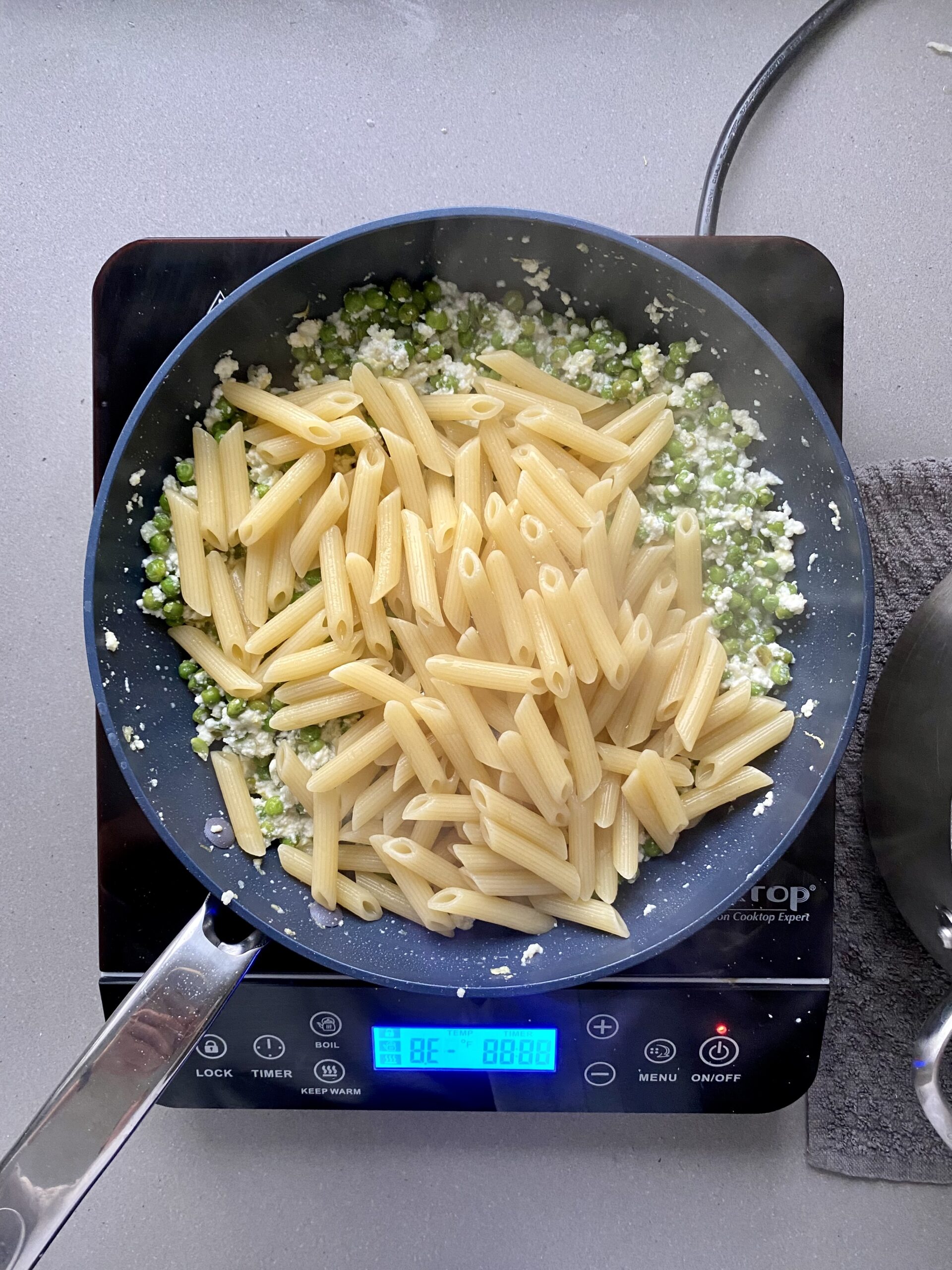 cooked penne pasta added on top of peas and ricotta.